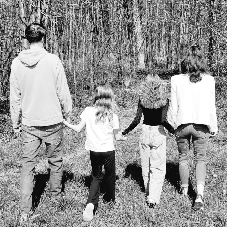 Eltern mit zwei Kindern laufen einen Waldweg entlang in einem Schwarzweiß-Foto