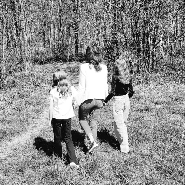 Mutter mit zwei Kindern läuft einen Waldweg entlang in einem Schwarzweiß-Foto