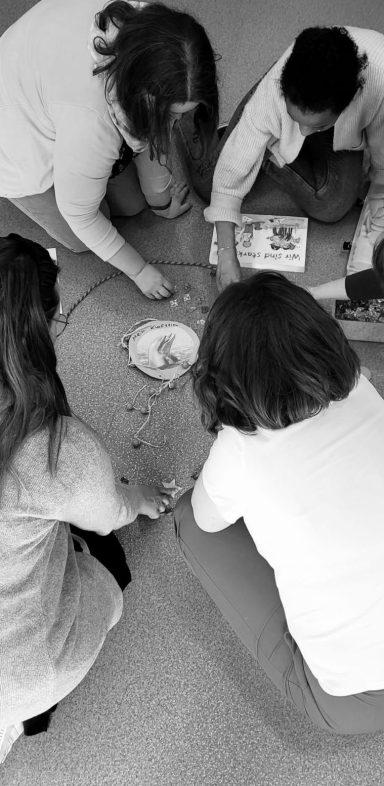 Workshop-Szene, in der vier Menschen gemeinsam am Boden sitzen und an etwas arbeiten