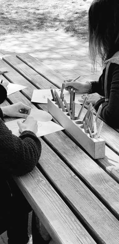 Zwei Menschen zeichnen an einem Tisch mit Stiften auf Blätter
